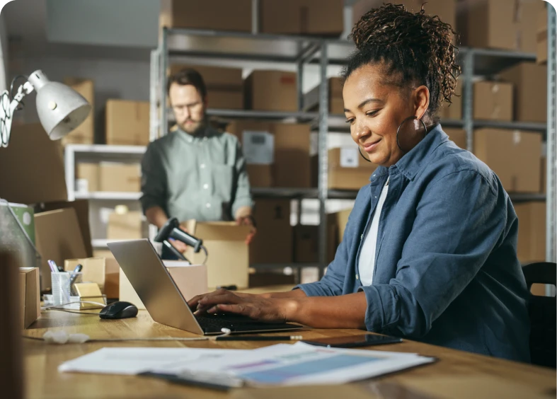 Woman working on laptop in warehouse